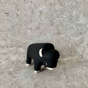 handmade and hand painted black wooden bison toy with white feet, ears and nose
